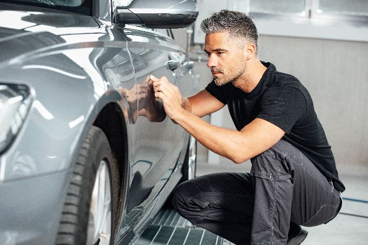 Person inspiziert Fahrzeug nach Lack und Karosserieschäden